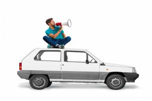 man-sitting-roof-car-with-megaphone-screaming