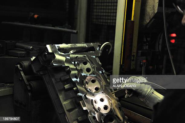 A woman works on a car head gasket at the "Fonderie du Poitou Aluminium" a foundry plant which is part of the Montupet group on January 19, 2012 in Ingrandes near Chatellerault. Montupet is a French-owned aluminium foundry and has long been recognised as an industry leader in the manufacture of complex cast aluminium components for the automotive industry worldwide. AFP PHOTO ALAIN JOCARD (Photo credit should read ALAIN JOCARD/AFP via Getty Images)